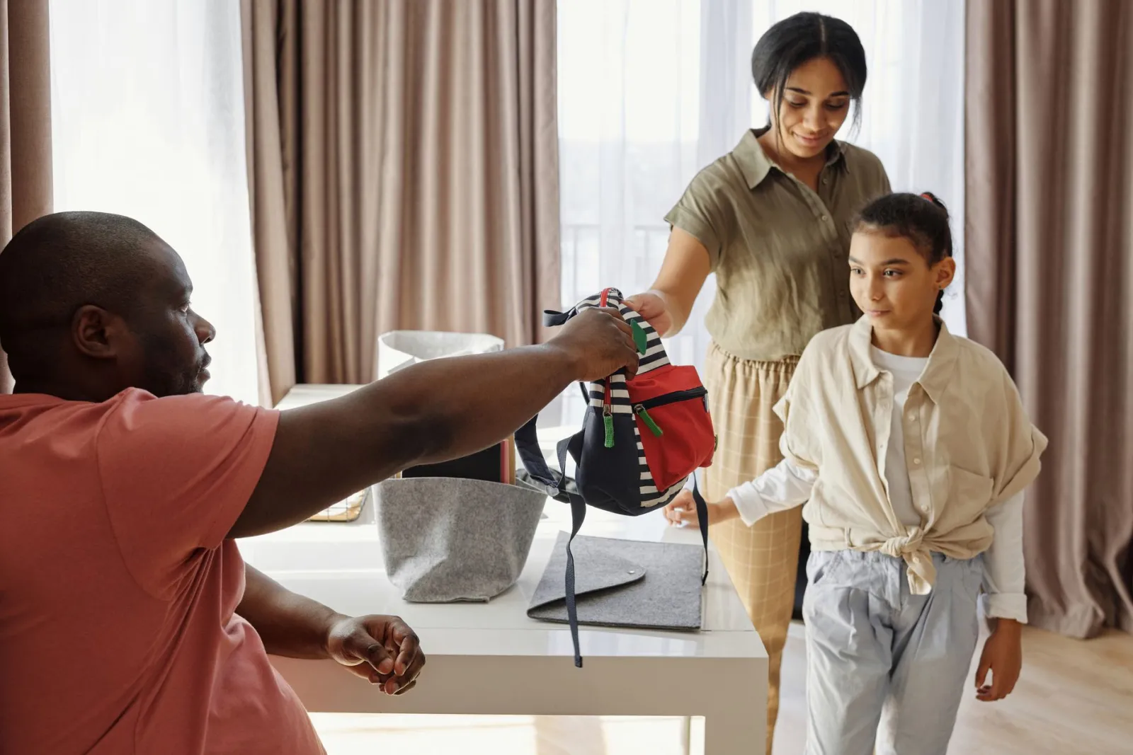 Family helping child get ready for school in a cozy indoor setting.