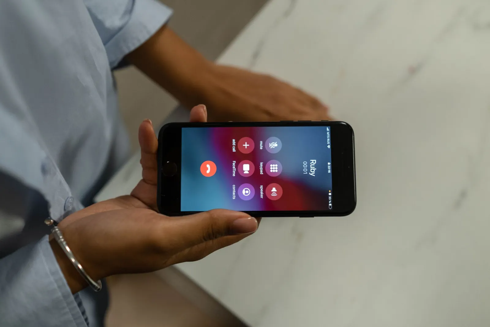 Close-up of a person holding a smartphone displaying an incoming call screen.