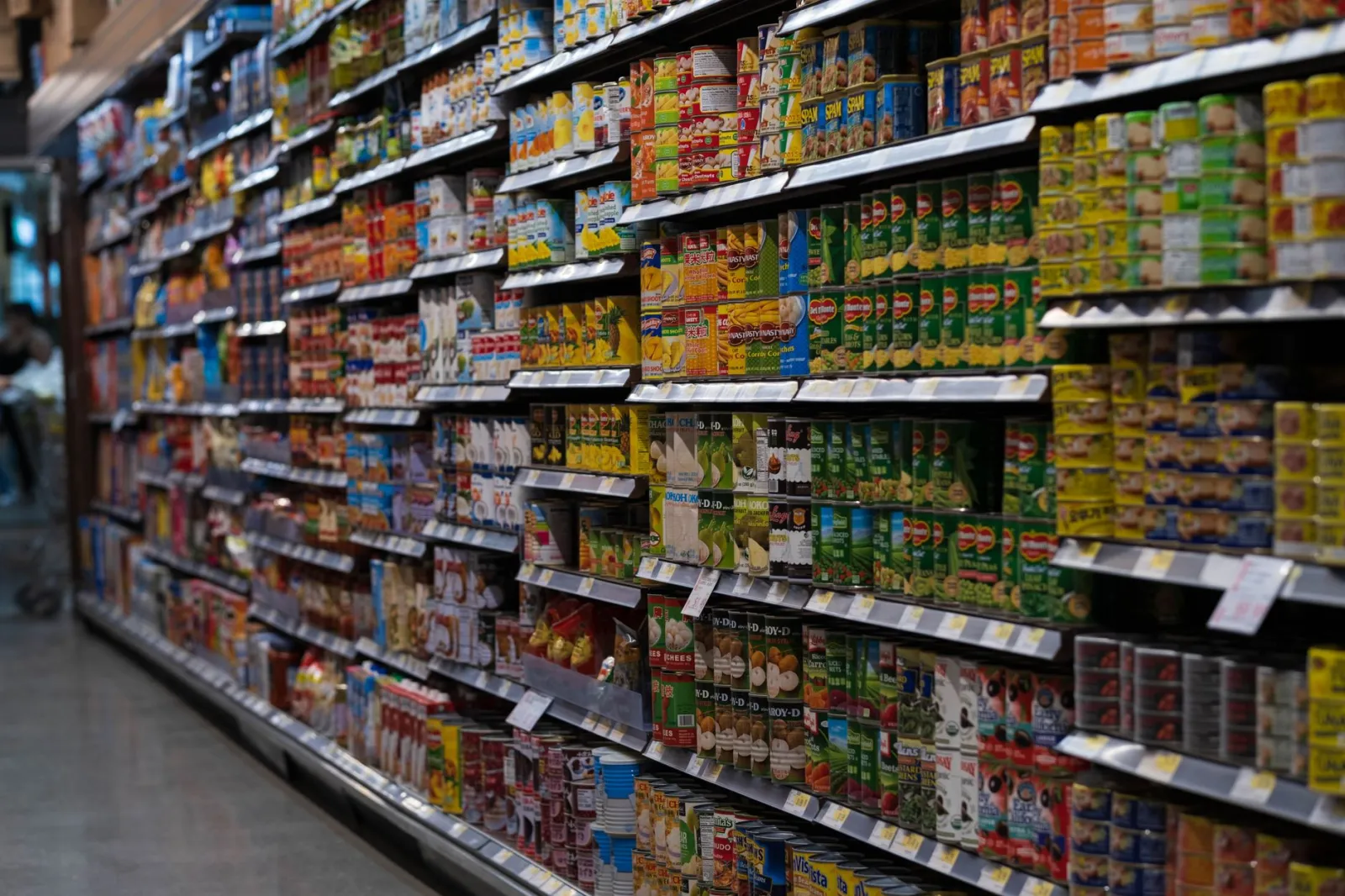 A supermarket aisle filled with various canned goods on shelves, showcasing retail diversity.